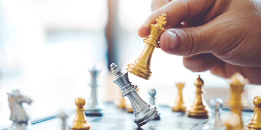 Hand holding gold and silver chess pieces